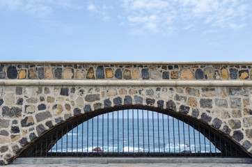 Fototapeta premium view through an old bridge arch to the atlantic