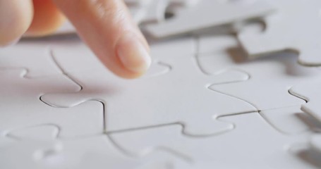 Female hand fitting a missing jigsaw puzzle in the correct hole.