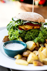 Vegan burger with lettuce, tomatoe, fried potatoes and garlic dill sauce