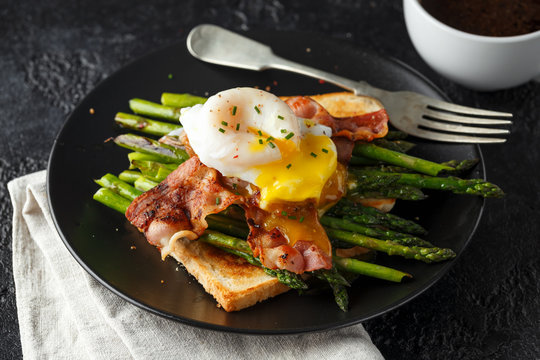Benedict poached Duck egg with crispy bacon and fried asparagus on toasts for breakfast