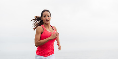 Young fit latin female athlete running