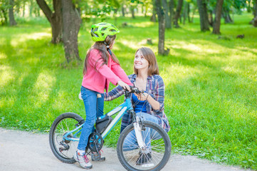 mom communicates with her daughter, teaching her how to ride a bicycle