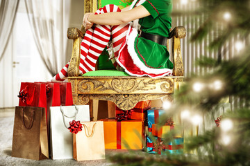 Slim young woman legs in christmas tights. Christmas tree and gifts. Home interior with big window. 