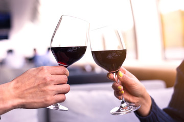 Selective focus of Mid adult Caucasian male and female hands toasting wine glasses in the room on...