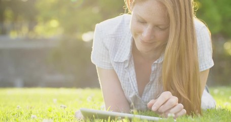 Woman using a tablet in a city park by sunset. Slow motion, medium shot. - Powered by Adobe