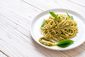 spaghetti with pesto sauce, olive oil and basil leaves.