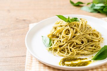 spaghetti with pesto sauce, olive oil and basil leaves.