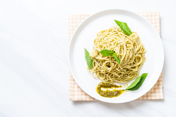 spaghetti with pesto sauce, olive oil and basil leaves.