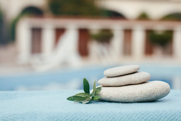 Zen stones tower. White spa stones with leaves on blurred blue background. 