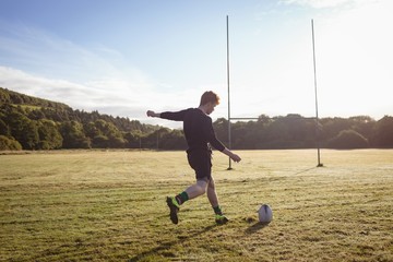 Rugby player kicking rugby ball in the field