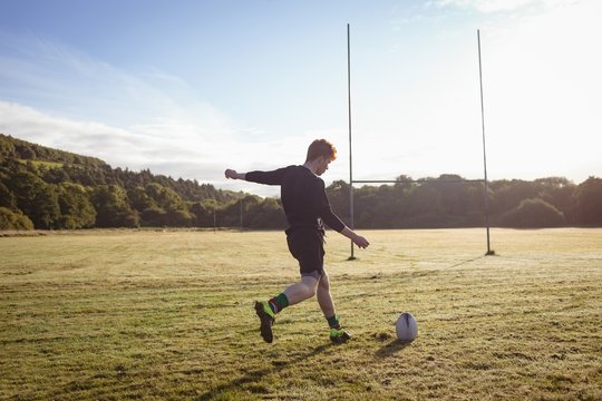Rugby player kicking rugby ball in the field - Powered by Adobe