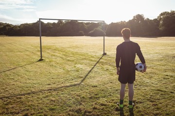 Football player standing with soccer ball in the field