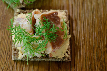 Canape with smoked Arctic char, paprika cream cheese and dill on rye bread. Delicious starter or cocktail snack. Table top view image with copy space.