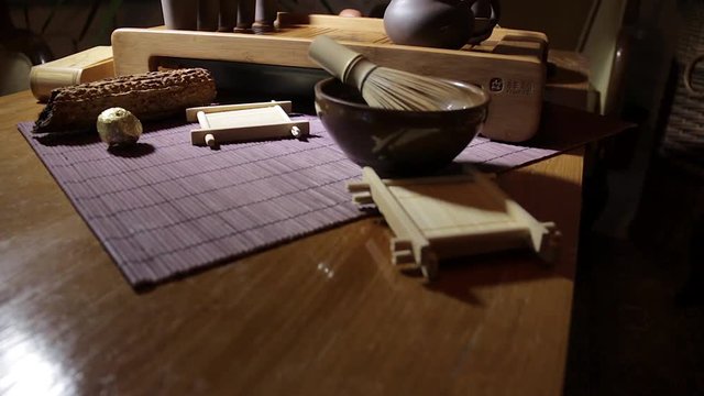 Wooden tea board with traditional Chinese cups and tipot for Chinese tea ceremony on the warm dark background.