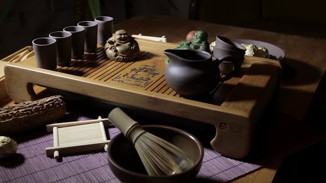 Wooden tea board with traditional Chinese cups and tipot for Chinese tea ceremony on the warm dark background.