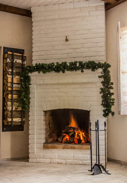 White brick fireplace decorated with a garland. Christmas Eve.