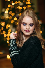 Beautiful young woman near the christmas tree. Christmas mood. Girl with fashion makeup