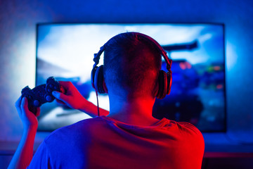 Rear view of a young player playing video games on an FPS console at home