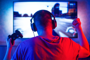 Rear view of a young player playing video games on an FPS console at home © Anton