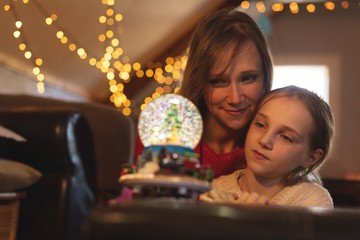 Mother and daughter looking at Christmas tree snow globe