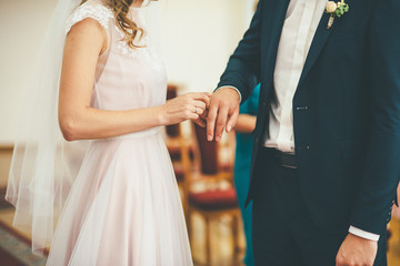 Bride puts a wedding ring on a grooms finger