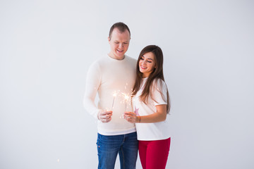 Valentine's Day concept - Young happy smiling cheerful attractive couple celebrating with sparklers on white background