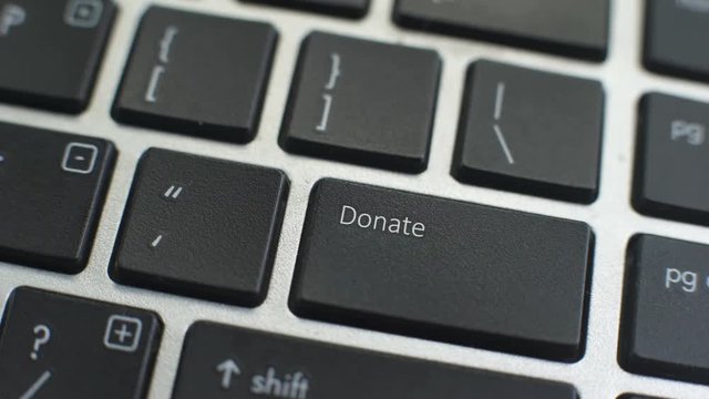 Donate button on computer keyboard, female hand fingers press key