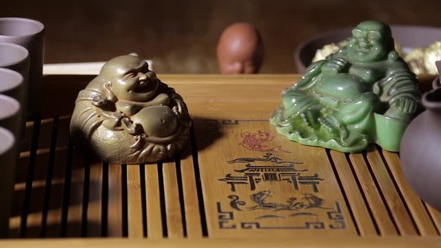 Souvenir clay figurines for Chinese tea ceremony with wooden tea board on the warm dark background.