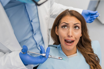 Dentist giving anesthesia to female patient