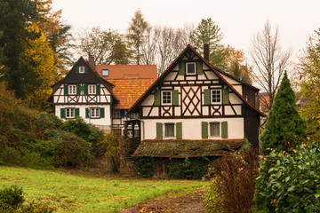 Obraz na płótnie Canvas Construcciones típicas de los pueblos alemanas. Casa con tablones de madera vistos, ventanas con contraventanas verdes, rodeado por bosque