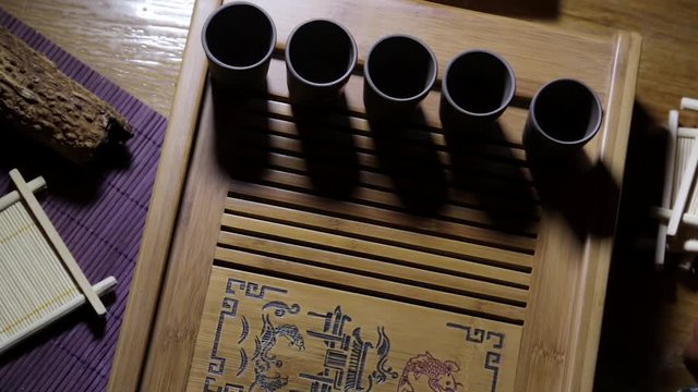 Wooden tea board with traditional Chinese cups and tipot for Chinese tea ceremony on the warm dark background.