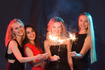 New year party, celebration and holidays concept - group of friends having fun with sparklers