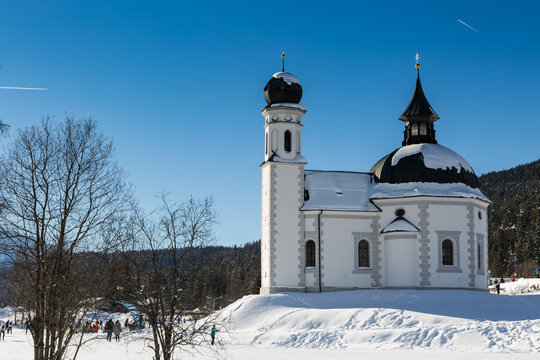 landmark Seekirchl church in Seefeld covered in snow on sunny winter day