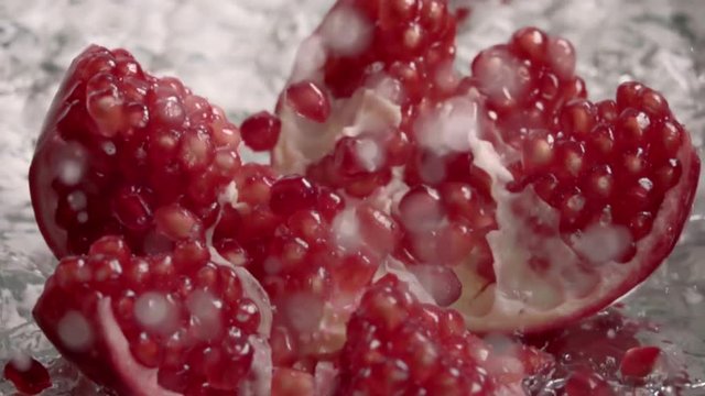 Falling splitted pomegranate into the water . Slow motion