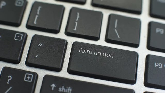 Donate in French button on computer keyboard, female hand fingers press key