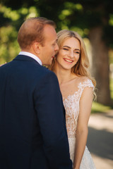 Naklejka premium Happy young couple in their wedding day spend time in park. Green background