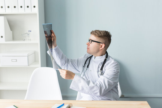 Portrait of a young doctor checking x-ray image in office