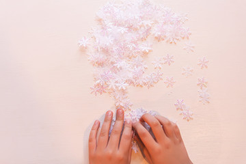 Child holds decorative paper snowflakes in hands.