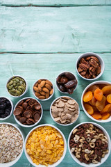 various cereals, nuts and dried fruits on wooden surface