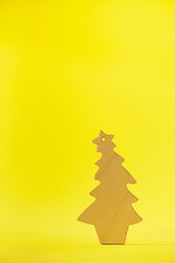 Wooden Christmas tree on yellow background with copy space. New Year party. Winter holiday concept. Greeting card in minimal style. Eco friendly decoration