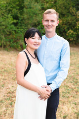 Obraz premium Asian pregnant women hugging with caucasian man outdoor