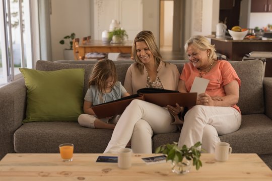 Multi-generation family looking at photo album in living room