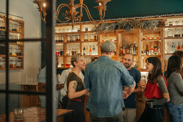 Group of friends standing in a bar having drinks together