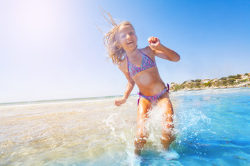 Happy girl jumping and splashing in shallow water