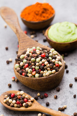 Peppercorn mix in a wooden bowl on grey table.