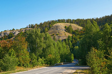 Asphalt road on a background of forest and mountains.