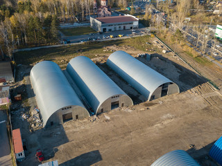 Aerial view of the three round storage rooms of the hangars on a bright autumnal autumn day. Industrial buildings for manufacturing.