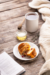 Cranberry bundt (wreath) cake served on white plate with tea mug and honey
