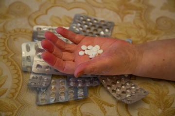 Female hand with a pill on the background of empty blisters of silver color
