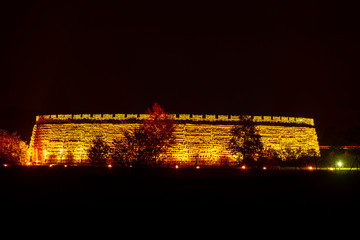eine orange angestrahlte Burg in der Nacht
